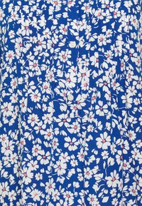 Blå blommig klänning med vita blommor och rosa mittar, knäppning fram och veckad textur. Materialet ser lätt och mönstrat ut.