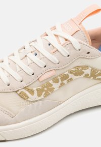 Sneaker in tela beige con accenti rosa chiaro, caratterizzato da un design laterale a stampa leopardo, lacci bianchi e suola testurizzata per una buona aderenza.