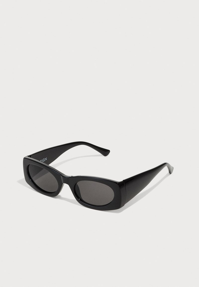 Occhiali da sole neri con montatura rettangolare, lenti scure e lati testurizzati. Presentano un design elegante e contemporaneo con silhouette audaci.