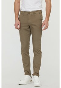 Ljusbruna slim-fit byxor i bomullsblandning, med knäppning och framfickor, kombinerat med vita sneakers.