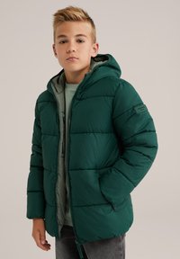 Zeleno napihnjeno jakno s kapuco, ki ima zadrgo in stranske žepke. Oblikovanje vključuje vodoravno šivanje in mehak notranji material.