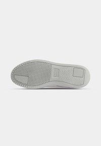 Suela de zapatilla gris claro con un patrón texturizado, que presenta un acabado suave y un área de marca central.