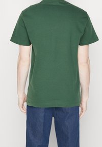 Grön bomull t-shirt med rund halsringning och korta ärmar, med en rak fåll och utan synliga motiv eller dekorationer.