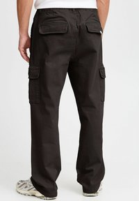 Schwarze Cargo-Hosen mit einer entspannten Passform, die zwei Gesäßtaschen und Seitentaschen aufweisen. Der Stoff ist robust und strukturiert.