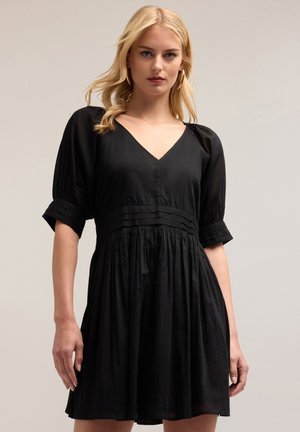Abito nero con scollatura a V, maniche a sbuffo e vita arricciata. Realizzato in tessuto leggero con gonna fluida e una sottile texture.