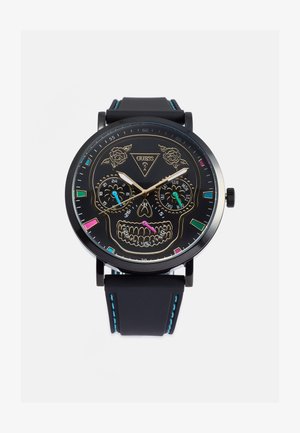 Schwarze Analog-Uhr mit einem Totenkopfdesign auf dem Zifferblatt. Verfügt über goldene Akzente, zwei Hilfszifferblätter und ein Gummiband mit blauen Nähten.