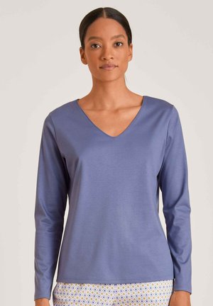 Langarm V-hals top van zacht, rekbaar paarse stof. Heeft een relaxte pasvorm en een gladde textuur. Gepaard met gestreepte broek.
