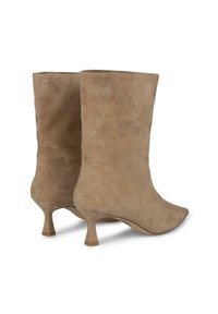 Stivaletti ankle in suede beige con punta affusolata, tacco medio curvo e texture liscia, dotati di un design minimalista e senza hardware visibile.