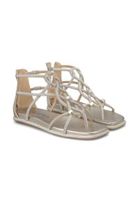 Sandali piatti con cinturini in tonalità oro e un design intrecciato, una soletta metallica e una suola texturizzata. Gli accenti includono piccoli dettagli in metallo dorato.