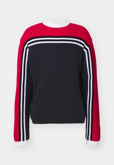 Kerek nyakú pulóver, piros felső résszel. Sötétszürke test és piros ujjak fekete és fehér csíkokkal. Kötött textúra.