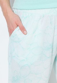 Pantaloni del pigiama a fantasia floreale azzurri chiari con una fascia elastica in vita e tasche laterali, realizzati in un tessuto morbido e testurizzato.