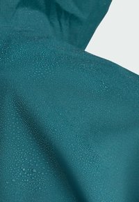 Teal waterproof fabric with droplets, showcasing a smooth texture and soft sheen. Focus on the material's durability and weather resistance.