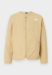 Lys beige, glidelåsjakke med rund hals, med brystlomme og logo på venstre side. Laget av glatt, lett stoff.