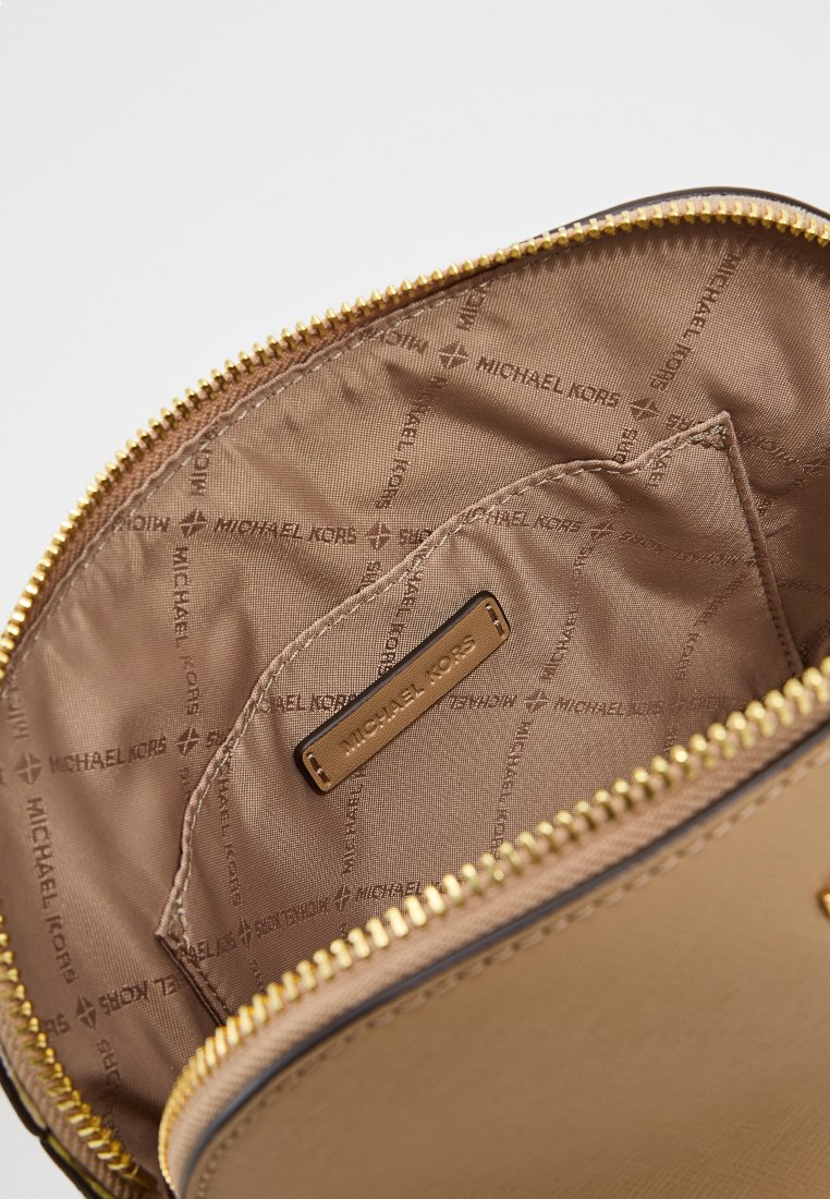 Intérieur de sac à main de couleur or avec doublure beige, comportant une étiquette de logo et une texture lisse, fermeture zippée et un compartiment spacieux.