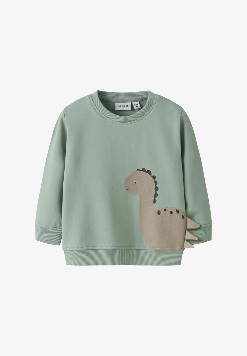 Sudadera verde de algodón con un gráfico de dinosaurio en beige en el frente, con puños y cuello acanalados, y una textura suave.