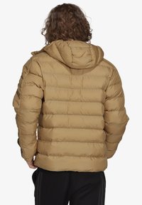 Tan pufferjakke med hætte, der har syede vandrette sektioner, elastiske manchetter og en afslappet pasform, lavet af glat, quiltet materiale.