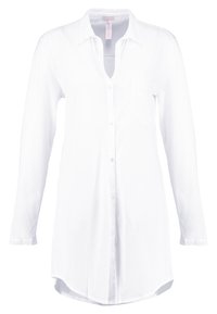 Camicia bianca a maniche lunghe realizzata in tessuto morbido, con una chiusura a bottoni sul davanti, colletto e una tasca sul petto, con orlo arrotondato.
