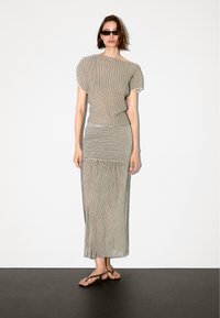 Gestreiftes Zweiteiler-Outfit mit einem kurzärmeligen, locker sitzenden Oberteil und einem langen Rock; Farben in Schwarz und Creme; leichtes Material.