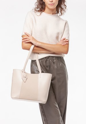 Borsa a tote in pelle beige con un pannello testurizzato, dotata di doppi manici e un tag decorativo. Materiale morbido e liscio con una forma strutturata.