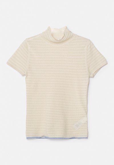 Bežs īsām piedurknēm turtlenecks tops, kas izgatavots no teksturēta adīta auduma ar loku rakstiem. Apakšmala ir ar gaiši zilu akcentu.