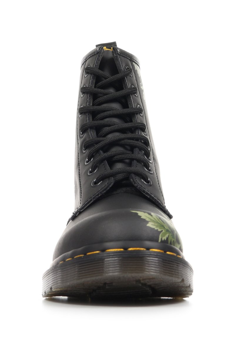 Schwarzer Leder-Schnürstiefel mit gelber Naht und grünem Blattmotiv auf der Schuhspitze, von vorne auf weißem Hintergrund fotografiert.