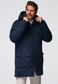 Marineblauwe geïsoleerde jas met capuchon, knoopsluiting aan de voorkant, opgestikte zakken en een gladde textuur, voorzien van gouden hardware accenten en een relaxte pasvorm.
