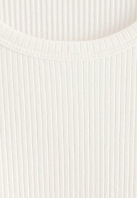 Tessuto bianco a coste con una morbida texture. Presenta un collo rotondo e strisce verticali equidistanti su tutta la superficie.