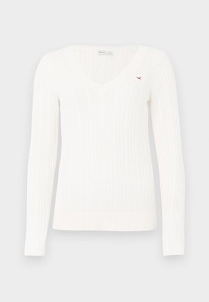 Biały sweter z dekoltem w serek, wykonany z dzianiny w warkocze, z długimi rękawami i małym czerwonym haftowanym logo ptaka na lewej piersi.