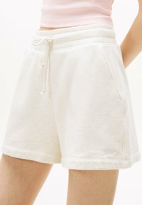 Pantalones cortos de mezcla de algodón blancos con cintura elástica, detalle de cordón y bolsillos laterales. Tejido suave y corte relajado.
