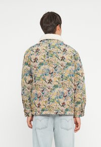 Floral-patterned jacket with a beige background, featuring blue, pink, and green flowers, and a white sherpa collar. Relaxed fit.