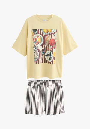 Kollane puuvillane T-särk, millel on värvikas toiduteemaline grafika, ja pruun-valge triibuline lühike püks. Lõdva istuvuse ja ümar kaelusega.