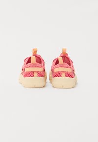Des baskets en maille rose avec un design texturé, des semelles beiges et des boucles pour un enfilage facile. À l'arrière, on aperçoit un léger talon et des bandes de soutien.