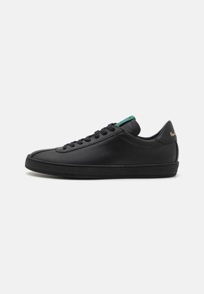 Adidași din piele neagră, cu vârf rotund, șireturi plate, accent verde pe limbă și siglă aurie pe toc. Talpă din cauciuc texturat.