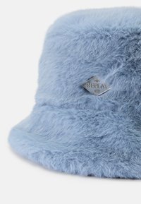 Lyseblå, fluffy bucket hat lavet af blødt materiale, med et sølvlogo, der har mærkenavnet "REPLAY" og året "1991."