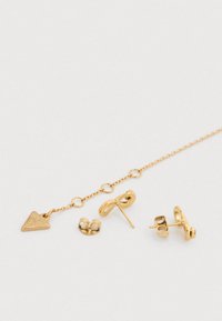 Σετ σκουλαρίκια σε χρυσό χρώμα που περιλαμβάνει ένα τρίγωνο μενταγιόν, ένα στριφτό σχέδιο, κλασικό καρφωτό και στρογγυλά καρφωτά, όλα σε αλυσίδα.