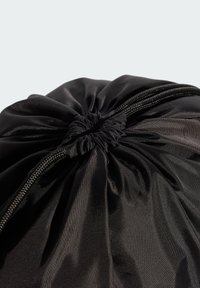 Čierna šnúrková taška vyrobená z hladkej, textúrovanej látky; zvrchu zošitá s čiernymi šnúrkami; minimalistický dizajn bez viditeľných kovových prvkov alebo ozdôb.