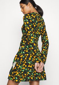 Vestido preto com um vibrante padrão de cerejas em laranja e verde. Mangas longas, corpete ajustado e saia rodada com fendas laterais.