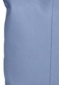 Lichtblauwe leren tas met een gestructureerd oppervlak. Heeft een naad langs één zijde en een afgeronde vorm met zachte contouren.