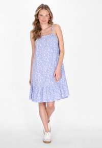 Rochie florală albastră cu bretele subțiri, tiv franjurat și material ușor, asortată cu adidași albi. Modelul prezintă flori albe mici.