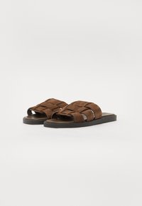Sandali a scivolo in suede marrone con fasce superiori intrecciate, design open toe e suole in gomma piatta per il massimo comfort.