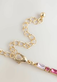 Złoty łańcuszek z owalnymi ogniwami, wyposażony w zapięcie typu homar i trzy prostokątne kamienie szlachetne w odcieniach purpury i różu. Gładka tekstura.