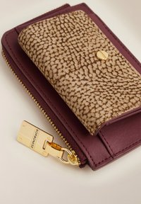 Leather wallet in burgundy with a textured beige flap. Features a gold zip closure and hardware accent. Smooth and embossed textures present.