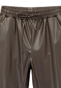 Brązowe, błyszczące, sztuczne skórzane dżinsy z elastycznym pasem i sznurkiem. Gładka tekstura i luźny krój.