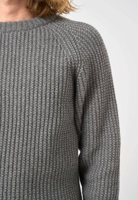 Grauer gerippter Strickpullover mit Rundhalsausschnitt, der ein strukturiertes Muster und lange Ärmel aufweist. Der Stoff wirkt weich und gemütlich.