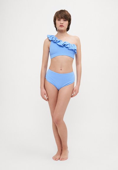 Světle modrý bikini s texturovaným povrchem. Top na jedno rameno má volánkový detail; kalhotky s vysokým pasem mají hladký design.