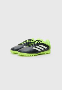 Zwarte voetbalschoenen met limoen groene accenten, een gestructureerde synthetische bovenkant, contrasterende witte strepen en een rubberen zool met kleine studs.