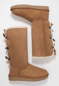 Bottes en daim beige jusqu'à la cheville et jusqu'au genou, avec une doublure en fourrure douce, des nœuds décoratifs sur les côtés et des semelles en caoutchouc texturées.