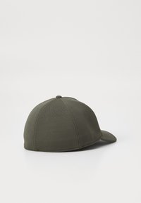 Grønn caps laget av teksturert stoff, med buet helm, seks-panel design og en knappdetalj på toppen.