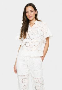Conjunto de dos piezas blanco bordado con patrones florales, con mangas cortas y un corte relajado, hecho de una tela ligera y texturizada.
