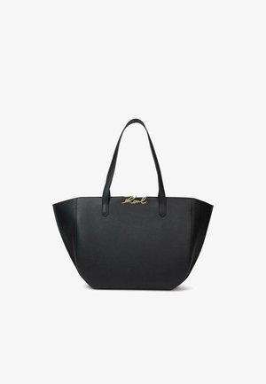 Sac cabas en cuir noir avec côtés larges, doubles anses et logo doré en écriture « Karl » en haut au centre.